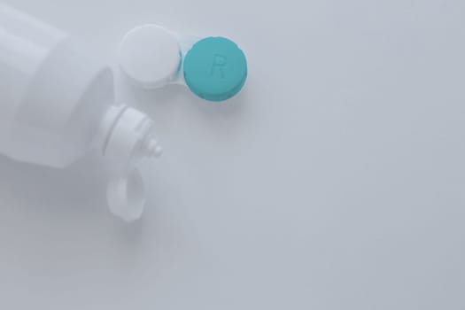 The lens container and the lens storage liquid lie on the side on a white background with space for text. top view, flat lay, copy space, isolate. High quality photo