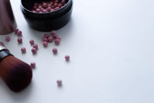 Blush balls of pink and cream color and a brush for applying blush on a white background with a place for text. top view, flat lay, copy space, isolate. High quality photo