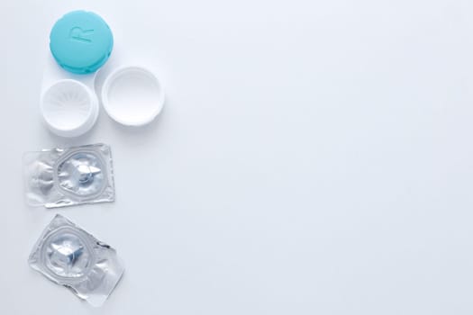 A container for lenses and two sealed lenses lie on the side on a white background with space for text.top view, flat lay, copy space, isolate. High quality photo