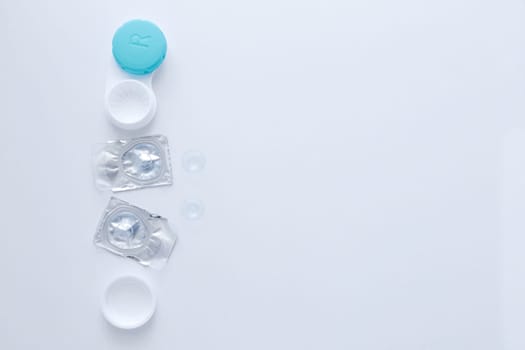 A container for lenses, two sealed lenses and lenses lying on a table on the side on a white background with a place for text. top view, flat lay, copy space, isolate. High quality photo
