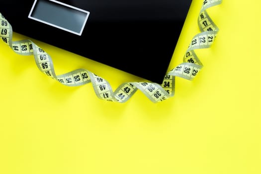 The scale and the yellow measuring tape are placed on a yellow background on top of the photo. top view, flat lay, copy space, isolate. High quality photo