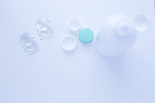 A lens remover, a lens storage container and two contact lenses lie on top of the photo on a white background. top view, flat lay, copy space, isolate. High quality photo