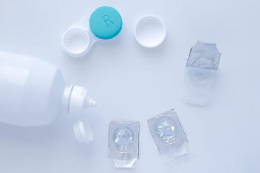 Lens remover, a container for storing lenses and two contact lenses lie on the sides on a white background, there is a place for text. top view, flat lay, copy space, isolate. High quality photo