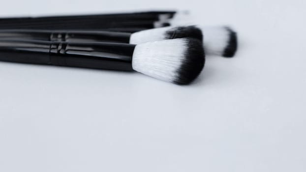Black brushes with white and black pile for makeup of different sizes lie on a white background on top.top view, flat lay, copy space, isolate. High quality photo