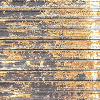 Metal shutter with peeling paint. Front view of a shutter rusted, deteriorated from elements. Ideal use for background, wallpaper.