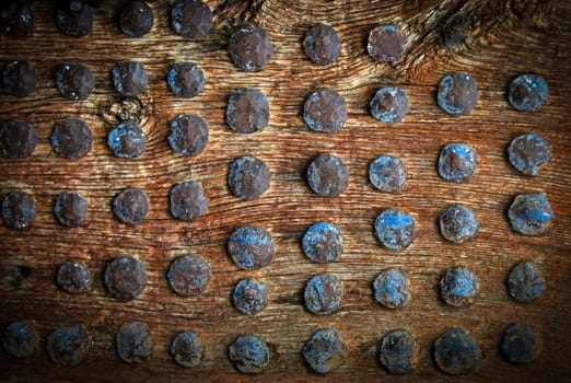 The vintage wooden surface with metal rivets. Selective focus