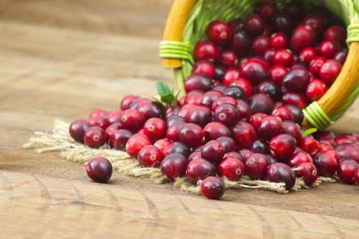 Cranberries in a basket on wooden background.