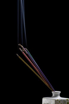 Burning incense sticks with smoke isolated on black