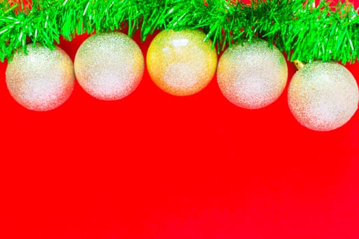 Christmas balls of silver color hang on a green fluffy garland tinsel of green color on top of the photo on a red background. top view, flat lay, copy space, isolate. High quality photo