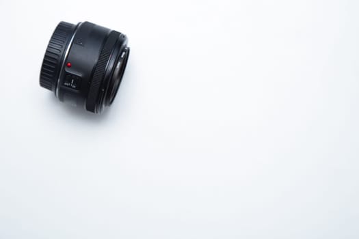A small fixed lens for a professional camera lies sideways on a white background. High quality photo