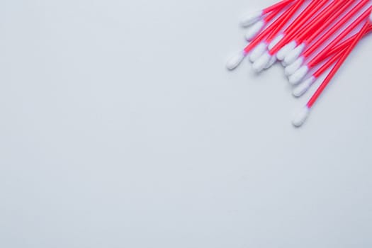 Disposable ear sticks with a red wand are lying on a white background in the upper corner. top view, flat lay, copy space, isolate. High quality photo