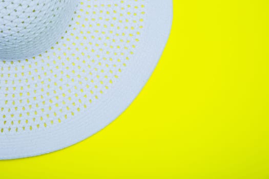 A white sun hat with a wide brim lies on a yellow background with a place for text. High quality photo