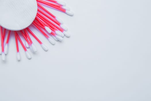 Disposable ear sticks with a red wand and white disposable cotton sponges lie on a white background.. top view, flat lay, copy space, isolate. High quality photo