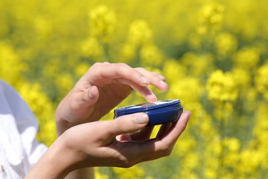 Close up of a woman hands holding moisturizer jar ready to apply in a yellow field