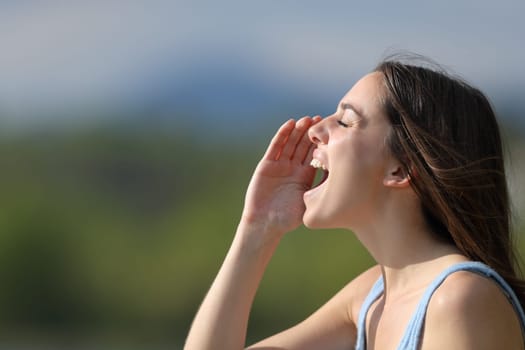 Profile of a woman shouting loudly in nature