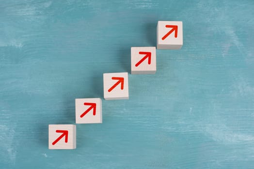 Red arrows going up on wooden cubes, blue background