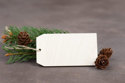 Empty sign with christmas decoration, branch of fir and cones, textured brown background