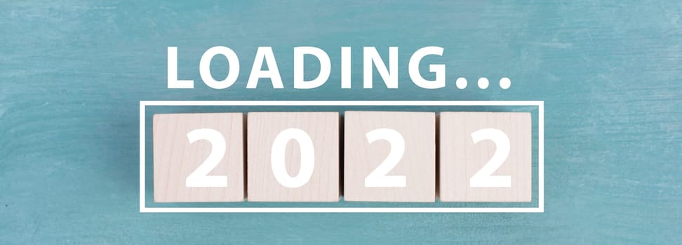 The year 2022 is standing in white letters on wooden cubes, the word loading is standing above