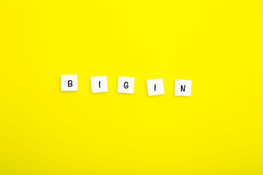 The word BEGIN is written in letters on small white squares on a yellow background. High quality photo