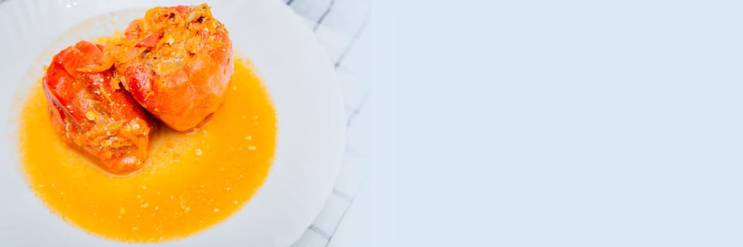 Red pepper stuffed with minced meat and carrots with onions lies on a white plate, which stands on a waffle napkin on a white background. High quality photo