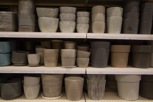 Pots for flowers of light and dark shades are on three shelves. High quality photo