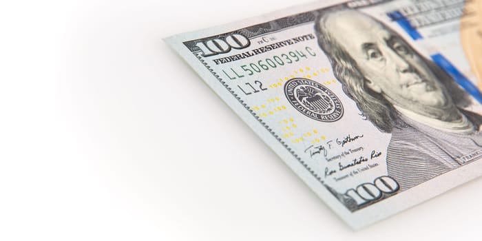 A hundred-dollar bill on a white background. The one hundred North American dollars bill is not fully positioned diagonally. Selective focus on a portion of the 100 bill. Color style. Place for logo, lettering, layout, layout.