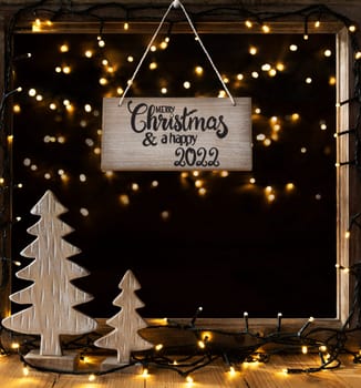 Window With Sign With English Calligraphy Merry Christmas And A Happy 2022. Night With Fairy Lights And Christmas Decoration Like Tree