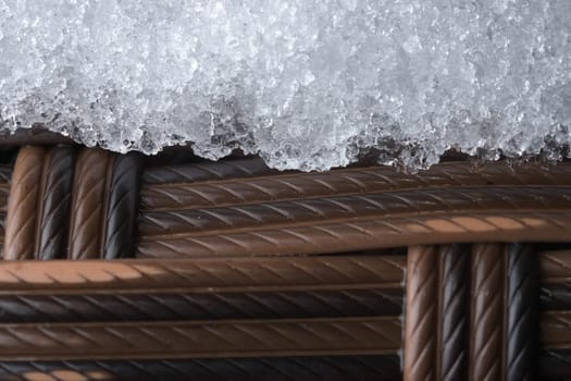 Icy plastic garden furniture. Rattan style weave, but synthetic material. Cold outdoor weather has caused a layer of snow or frost to settle.