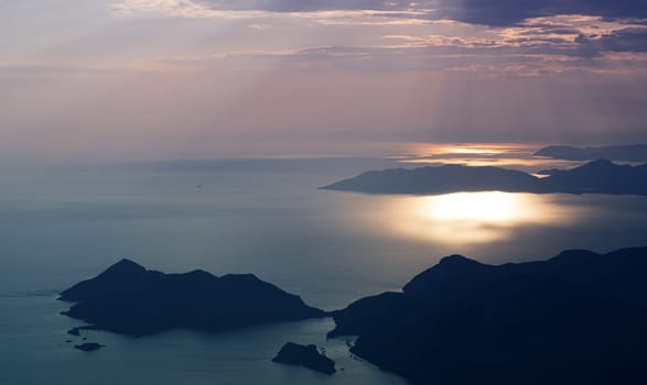 beautiful aerial panorama from the Babadag peak of high mountains rising up over the Mediterranean sea at sunset near Oludeniz Blue Lagoon coast in Turkey during summer