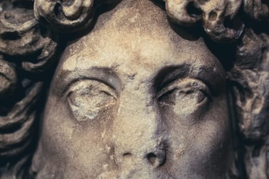 front view closeup of woman antique white marble statue with damaged eyes