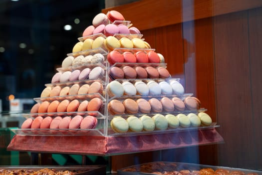 side view closeup of colorful assorted macarons cakes arranged in pyramid shape in candy store window