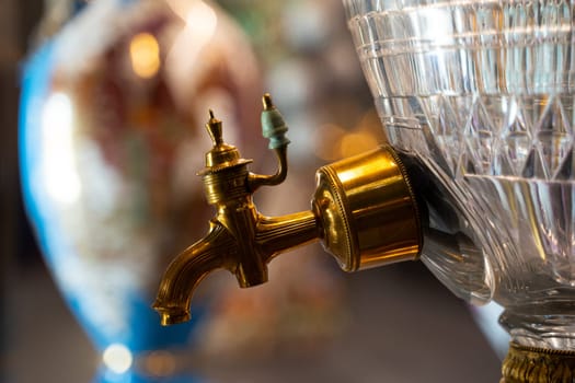 side view closeup of beautiful gold plated spigot with ceramic handle of luxurious glass samovar