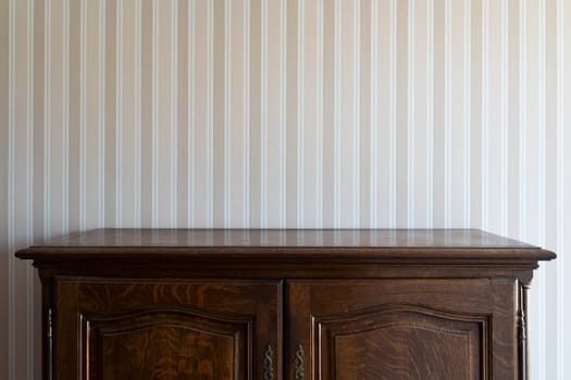 front view close up of empty brown vintage drawer wooden cabinet against a white wall with beige stripes