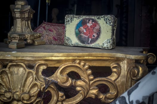 Old tin box over golden table. .Antiques dealer shop window