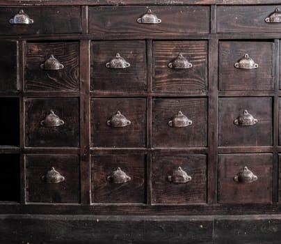 Dark brown wooden drawers furniture. Shell-shaped metal handles