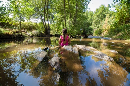Child girl discovering Gevora river, La Codosera, Badajoz, Extremadura, Spain. Idyllic location of crystal clear waters and riverside forests