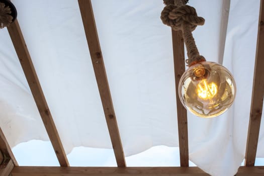 Rope light bulb over canvas pergola cover. Low angle view