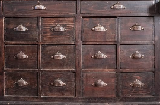 Dark brown wooden drawers furniture. Shell-shaped metal handles