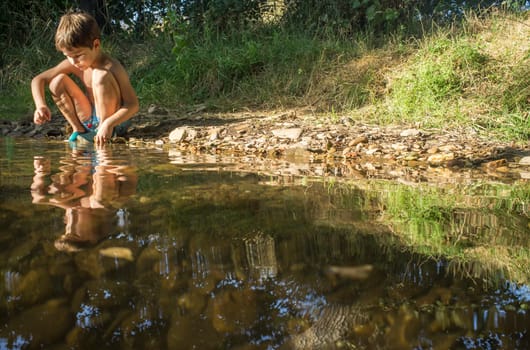 Little boy exploring clear mountain riverside. Holidays where kids can go wild concept