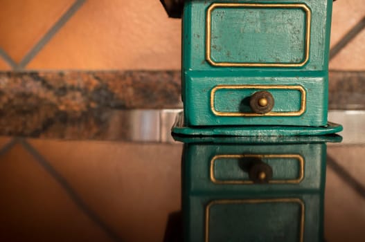 Old manual coffee grinder painted gold and green. Selective focus