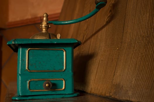Old manual coffee grinder painted gold and green. Selective focus