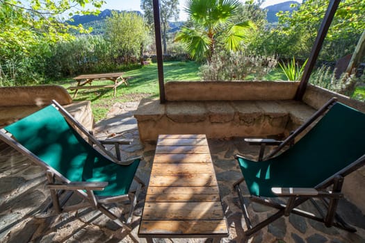 Porch country house with folding canvas deckchairs. Rural tourism concept