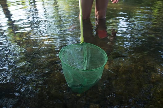Little girl playing with fishing net in the river. Holidays where kids can go wild concept