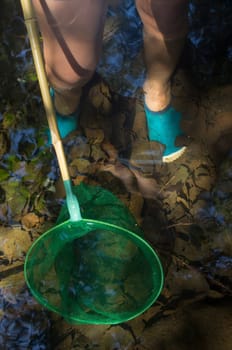 Little boy playing with fishing net in the river. Holidays where kids can go wild concept