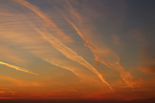 Red sky lit by the setting sun, aircraft trails