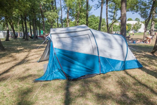 Camping tent at wild campsite surrounding the pine forest on summer sunny daylight.