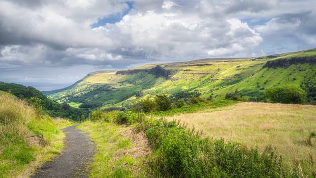 Trail or footpath in Glenariff Forest Park leading between hills to beautiful green valley, Antrim, Northern Ireland