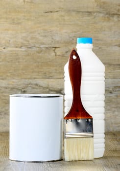 bottle, paint pot and brush on the wooden table