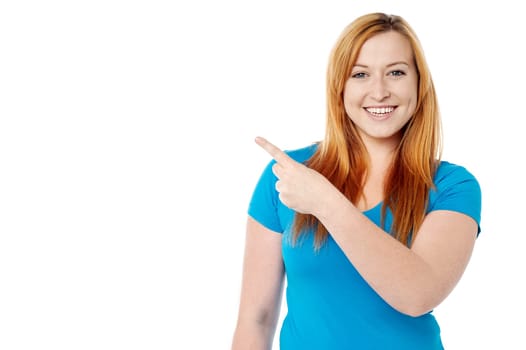 Smiling young woman pointing at copy space