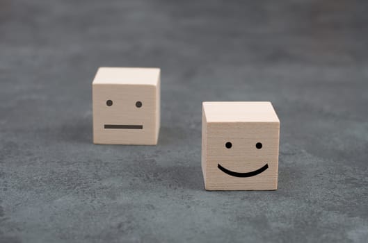 Wooden cubes with a happyand a sad face on a dark background, symbol
